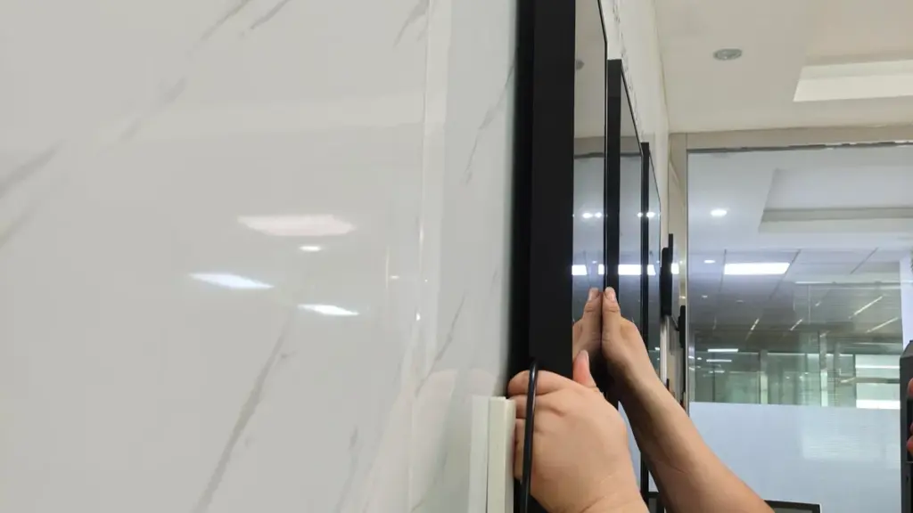 A technician installing a slim flat screen monitor on a wall